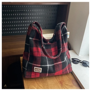 Detail of red and black plaid velvet tote bag with bear leather patch and books