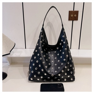 Detail of black rivet hobo bag showing large capacity and studded texture next to a phone