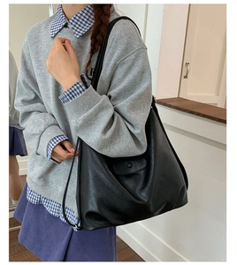 Detail of a large black matte PU leather tote bag shown on model for daily commute