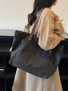Retro large capacity black canvas tote bag with brown leather handles worn by model