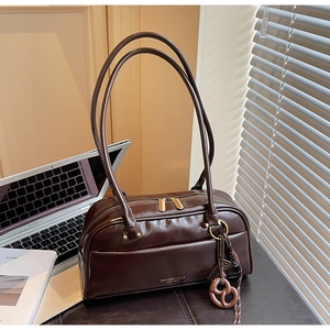 Détail du sac oreiller marron foncé brillant avec logo doré et finitions raffinées