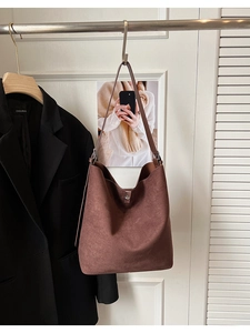 Detail view of coffee brown suede bucket bag with thick shoulder strap and silver buckle