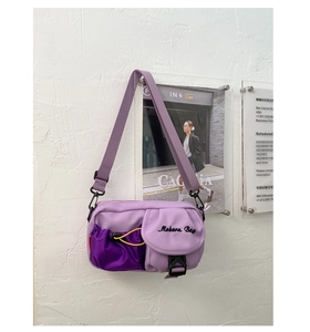 Detail of purple nylon crossbody bag featuring mesh pocket, buckle closure and logo embroidery