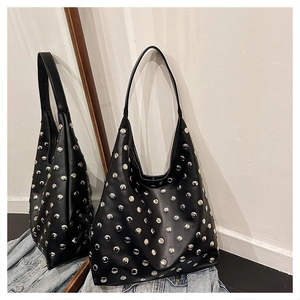 Close-up of black leather hobo bag featuring silver metal rivets and curved silhouette