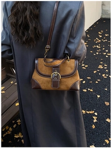 Scatto esterno di una borsa a tracolla in pelle scamosciata marrone con un cappotto lungo