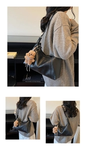 Detail of black soft leather hobo bag with stitching and a cute bear charm pendant
