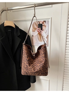 Detailed view of leopard print bucket bag hanging against a stylish blazer backdrop
