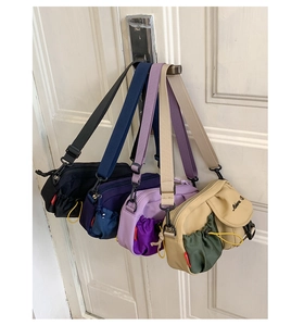 Detail of four colorful nylon crossbody bags with drawstrings hanging on a white door
