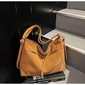 Detail of caramel leather tote bag showing golden hardware and detachable shoulder strap