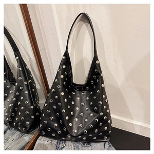 Detail view of black leather tote bag featuring decorative silver metal rivets and punk design
