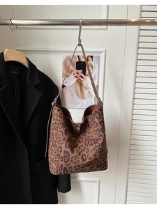 Close-up of retro leopard print tote bag with brown leather strap hanging in a scene