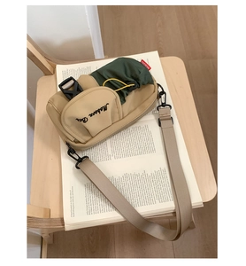 Detail of khaki and green crossbody bag featuring Moborn embroidery and plastic buckles
