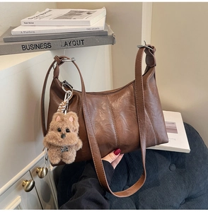 Detail of dark brown vintage shoulder bag with textured leather and plush puppy charm