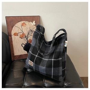 Detailed close-up of a plaid plush tote bag featuring a BEAR patch on a leather bench