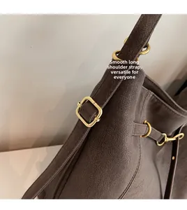 Close-up of smooth adjustable long strap and gold metal hardware on brown tote bag