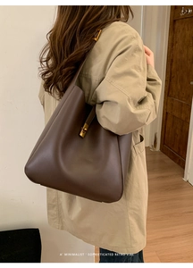 Detail of dark brown leather bucket bag with gold metal twist lock on a khaki coat