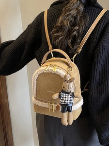 Chic khaki faux suede backpack with white plush trim and cute bunny charm on model