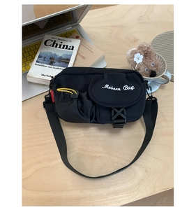 Detail of a black nylon crossbody bag with Moborn Bag embroidery and yellow drawstring pocket