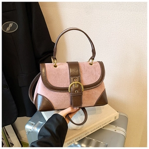 Detail of vintage saddle bag featuring pink suede, brown leather, and a large gold buckle