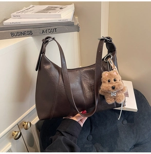 Detail of coffee brown retro hobo bag with a cute plush dog pendant and adjustable strap