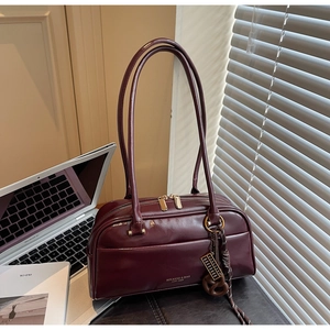 Détail du sac oreiller rétro bordeaux avec fermeture éclair dorée et logo