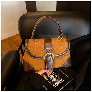 Detail of vintage suede saddle bag with gold oval buckle on a black leather chair