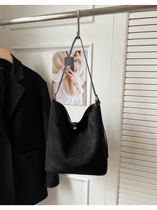 Macro detail of black matte faux suede bucket bag with silver metal magnetic buckle