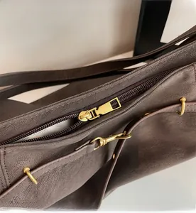 Detailed macro view of the smooth gold metal zipper and dark brown textured leather