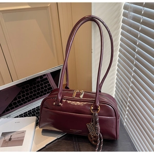 Détail d'un sac oreiller bordeaux avec zips dorés et pendentif boulier sur bureau