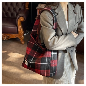 Detail shot of a plaid tweed tote bag styled with a grey blazer and white pleated skirt