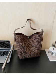 Macro detail of leopard print tote bag featuring a leather strap and gold metal twist lock