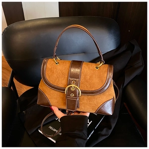 Close-up of vintage brown suede and leather saddle bag with gold buckle on chair