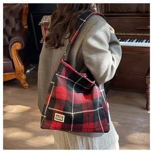 Detail showing the red and black plaid flannel texture and BEAR logo patch of the tote bag