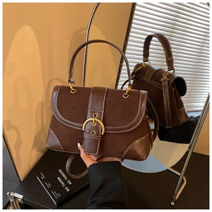 Detail of vintage saddle bag with contrast stitching and golden hardware on dark base