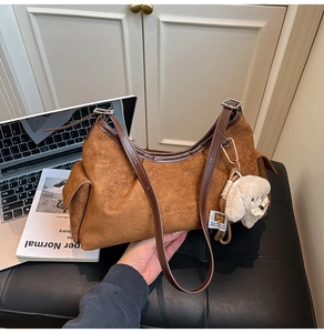 Détail du sac dumpling en daim marron avec bandoulière en cuir et breloque chien