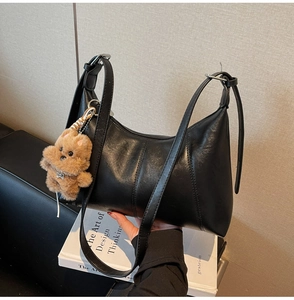 Detail view of black moon shoulder bag with leather texture and bear charm