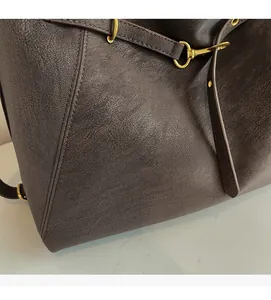 Detail of dark brown lychee texture leather bag with gold metal buckle and strap