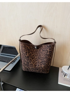 Detail of leopard print bucket bag featuring brown leather strap and silver turn-lock closure