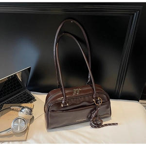 Détail du sac bowling en cuir verni marron foncé avec ferrures argentées et bandoulières