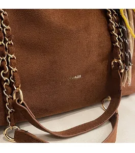 Gros plan sur un sac bandoulière en daim marron avec chaîne dorée et texture cuir