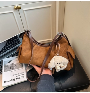 Détail d'un sac hobo en daim marron avec bandoulière réglable et pendentif chien en peluche