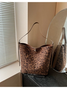 Detail of leopard print bucket bag with brown leather strap and metal twist-lock buckle