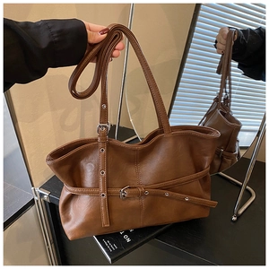 Gros plan du sac cabas marron avec lanières décoratives et boucle métallique