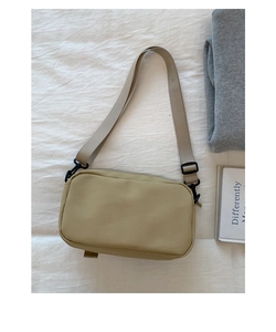 Detail view of khaki retro utility crossbody bag with adjustable strap on fabric background