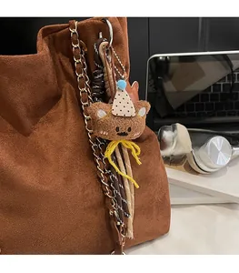 Détail d'un ours en peluche marron avec chapeau de fête et corde tressée sur un sac