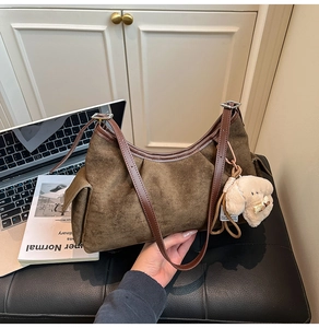Détail d'un sac demi-lune en daim marron avec poches latérales et breloque chiot en peluche