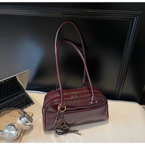 Sac oreiller bordeaux en cuir avec fermeture dorée et détail de pendentif tressé