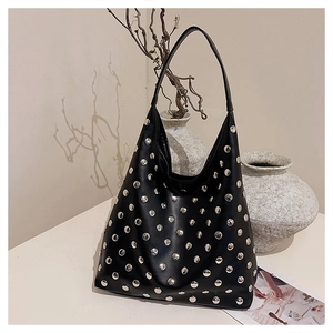 Close-up of black leather tote bag with silver studs and wide shoulder strap