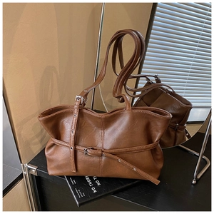 Détail du sac cabas marron caramel avec boucle décorative et texture plissée élégante