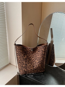 Close-up of leopard print bucket bag with silver twist lock on top of books